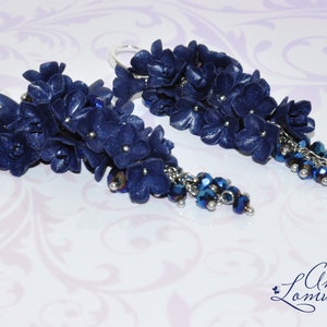 May include: A pair of dangle earrings with a cluster of dark blue polymer clay flowers and a silver chain with dark blue crystal beads.