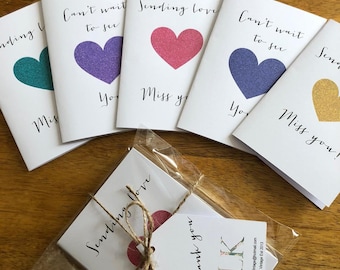 May include: Five small cards with glitter hearts and the text "Can't wait to see you" and "Sending love, Miss you". The cards are packaged in a clear plastic bag with a brown twine bow and a tag that says "Thank you".