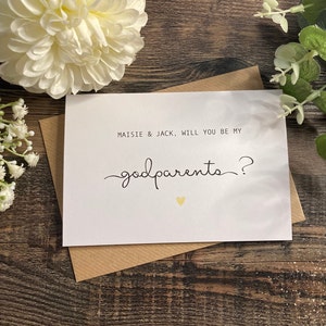Pu&ograve; includere: Carta bianca con testo nero che dice "Maisie & Jack, volete essere i miei padrini?" con un piccolo cuore dorato.