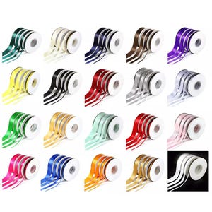 May include: A collection of spools of satin ribbon in various colors, including green, yellow, black, red, silver, and pink. Each spool is neatly rolled, with the ribbon cascading out in graceful curves. Ideal for crafting and gift wrapping.