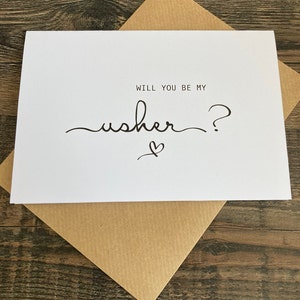 May include: White card with black text that reads "Will you be my usher?" with a small heart drawn underneath the text.