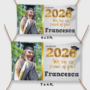 May include: A white ceramic mug with a black handle and the text "But First, Coffee" in a bold, black font. The mug is set against a blurred background. The mug appears to be approximately 10 cm tall.