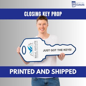 May include: A large, white key-shaped prop with a blue border, held by a person. The key features the text "REAL ESTATE" and "JUST GOT THE KEYS!". The prop is designed for real estate closing events.