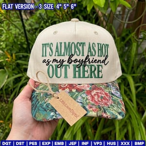 May include: A cream-colored baseball cap with a floral patterned brim. The front features embroidered green and black text that reads: IT'S ALMOST AS HOT as my boyfriend OUT HERE. A brown cardboard tag labeled LittleLoomDigital is attached.