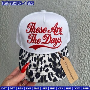 Könnte beinhalten: Weiße Baseballkappe mit dem gestickten Text "These Are The Days" in roter Schrift. Die Kappe hat einen Leopardenmuster-Schirm und ein kleines Etikett mit "LittleLoomDigital".