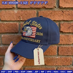 May include: A navy blue baseball cap with an embroidered design featuring an eagle, American flag, and the words "United States 2026 25th Anniversary." The cap has a curved brim and a tag that says "LittleLoomDigital."