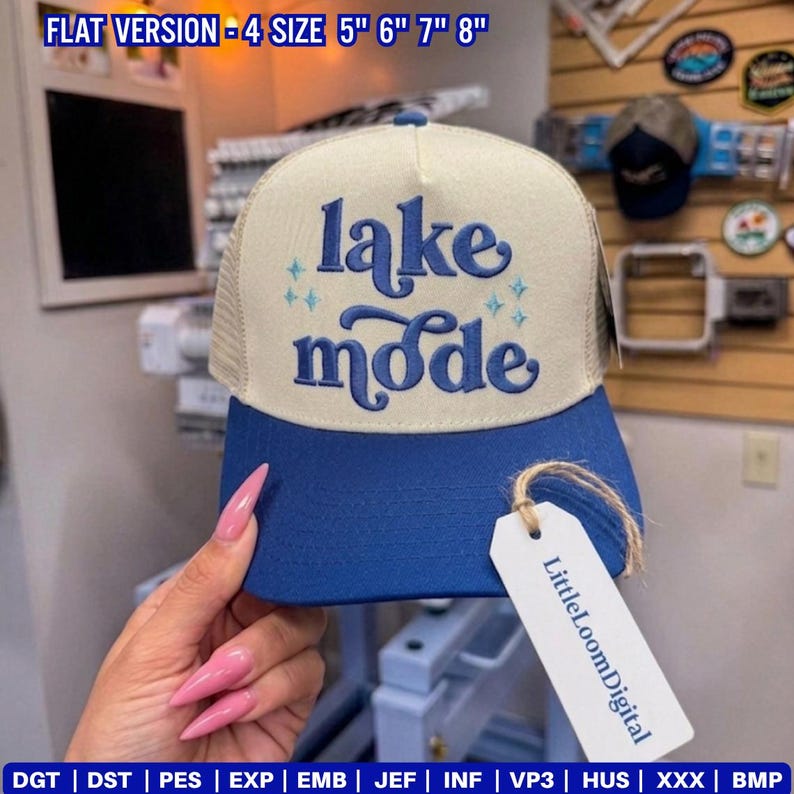 May include: A blue and beige trucker hat with the words "lake mode" embroidered on the front. The hat has a mesh back and a curved brim. A tag with the text "LittleLoomDigital" hangs from the hat.