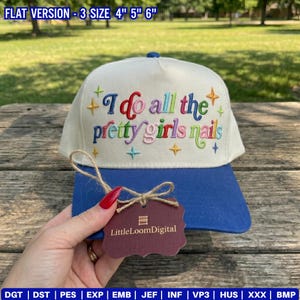 May include: A cream-colored baseball cap with a blue brim featuring the embroidered text "I do all the pretty girls nails" in multi-colored cursive lettering, accented by small embroidered stars. A brown tag labeled "LittleLoomDigital" is attached.
