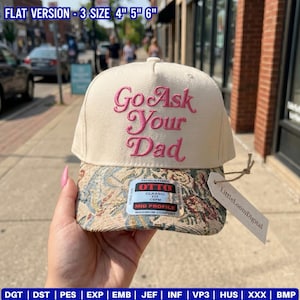 May include: A cream-colored baseball cap featuring the embroidered pink text Go Ask Your Dad on the front panel. The brim displays a multi-colored floral tapestry pattern. An Otto brand sticker is centered on the brim, and a paper tag is attached.