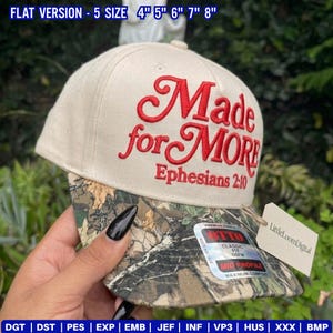 May include: A beige baseball cap with the words "Made for MORE" embroidered in red, along with "Ephesians 2:10." The brim features a camouflage pattern. The hat has a tag that says "LittleLoomDigital."