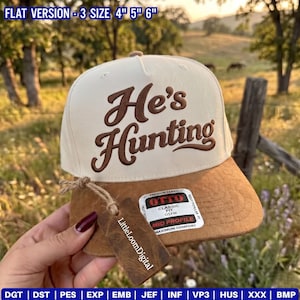 Könnte beinhalten: Eine cremefarbene Baseballkappe mit einem braunen, wildlederartigen Schirm und dem braun gestickten Text "He's Hunting" auf der Vorderseite. Ein rechteckiges braunes Holzschild ist mit einer Schnur befestigt, und ein Aufkleber auf dem Schirm zeigt "OTTO CLASSIC FIT".