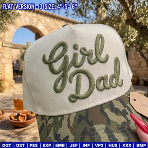 May include: A beige baseball cap with the words "Girl Dad" embroidered in green script. The brim features a camouflage pattern in shades of green, brown, and tan. The hat is available in three sizes: 4", 5", and 6".