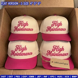May include: Four baseball caps with a white crown and a bright pink brim. The phrase "High Maintenance" is embroidered in a cursive font on the front of each cap. The caps are stacked inside a cardboard box.