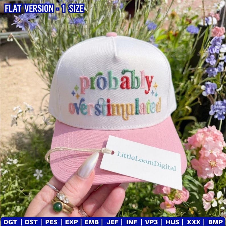 May include: A white and pink baseball cap with the embroidered phrase "probably overstimulated" in colorful letters. The cap has a curved brim and a tag that reads "LittleLoomDigital".