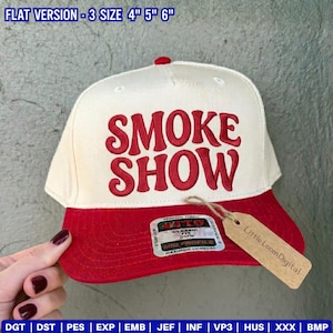 May include: A baseball cap with a red brim and a cream-colored crown. The cap features the words "SMOKE SHOW" in red, bold lettering. The text "FLAT VERSION - 3 SIZE 4" 5" 6"" is at the top. A tag with "Little Loom Digital" is attached.