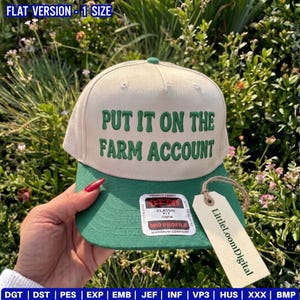May include: A beige and green baseball cap with the text "PUT IT ON THE FARM ACCOUNT" in green. The cap has a green brim and a tag that says "LittleLoomDigital". The hat is a classic fit, mid profile, and made of premium fabric.