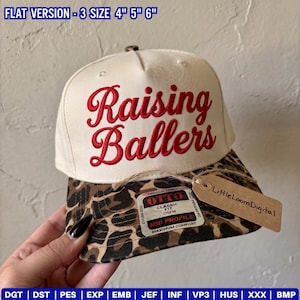 May include: A cream-colored baseball cap with a leopard print brim. The front features the red embroidered text Raising Ballers. A sticker on the brim reads Otto Classic Fit OSFM Mid Profile. A brown paper tag reads LittleLoomDigital.