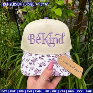 以下が含まれることがあります： 紫色の「Be Kind」の刺繍が入ったベージュ色の野球帽。つばには白と紫の花柄模様があります。「Little Loom Digital」と書かれたタグが付いています。