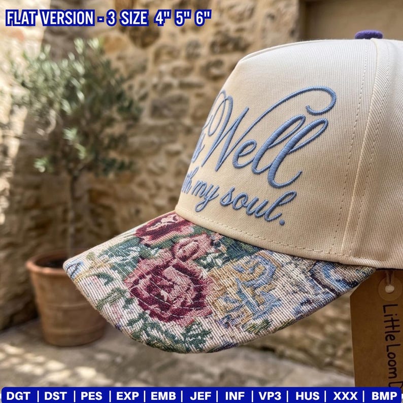 May include: A cream-colored baseball cap with the embroidered text "Well my soul." The brim features a floral tapestry design with burgundy, pink, and blue hues. The cap has a purple button on top.