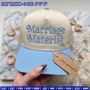 May include: A light blue and beige trucker hat with the embroidered text "Marriage Material". The hat has a mesh back and a curved brim. The tag reads "Little Loom Digital".
