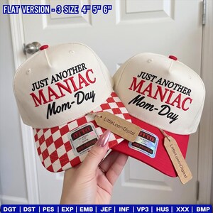 Op de afbeelding: Twee off-white baseballpetten met rode borduursels met de tekst JUST ANOTHER MANIAC Mom-Day. Eén pet heeft een rood-wit geblokte klep, terwijl de andere een effen rode klep heeft. Beide zijn voorzien van Otto-stickers en bruine labels.