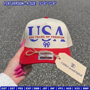 May include: A red and cream-colored trucker hat with the word "USA" in blue, along with "250 YEARS OF FREEDOM." The hat has a mesh back and a tag that says "Little Loom Digital."