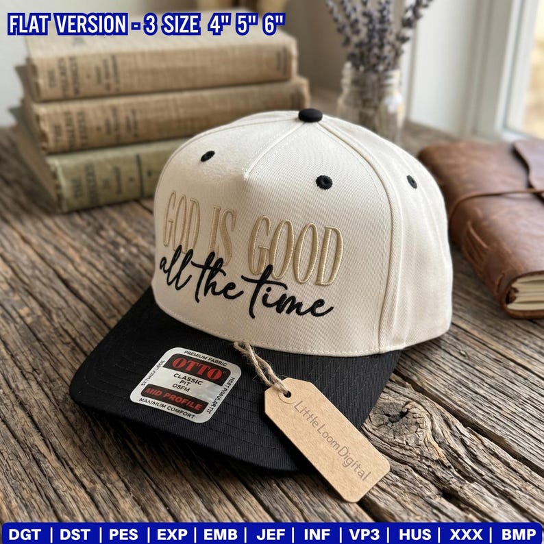 May include: A cream-colored baseball cap with a black brim. The cap features the embroidered phrase "GOD IS GOOD all the time" in gold and black thread. A tag from "Little Loom Digital" hangs from the cap.