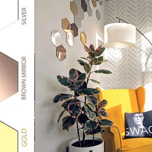 Puede incluir: Un sill&oacute;n amarillo con un coj&iacute;n negro que dice "SWAG". Una gran planta en maceta est&aacute; al lado del sill&oacute;n. La pared detr&aacute;s del sill&oacute;n tiene un patr&oacute;n geom&eacute;trico de espejos hexagonales plateados.