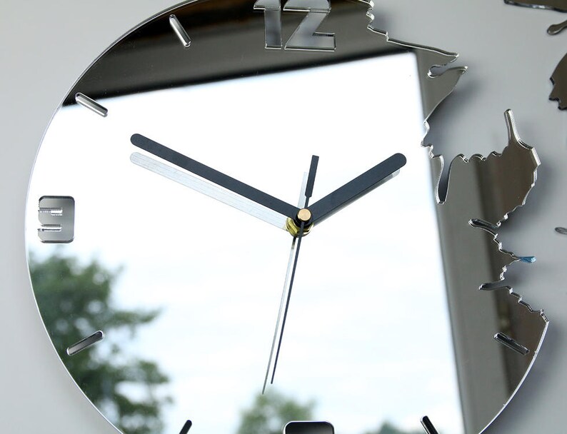 May include: A silver mirrored clock with black hands and Roman numeral markings. The clock face is surrounded by a decorative, irregular, mirrored frame.
