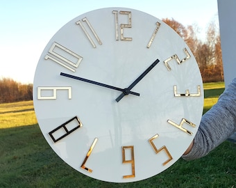 May include: White round clock with gold Roman numeral hour markers and black hands.