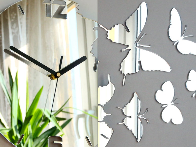 May include: A silver mirrored clock with black hands and Roman numeral markings. The clock is surrounded by silver mirrored butterflies.