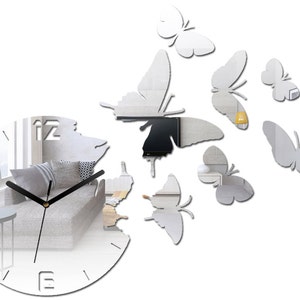 May include: A silver mirrored clock with black hands and Roman numerals. The clock is surrounded by eight silver mirrored butterflies.