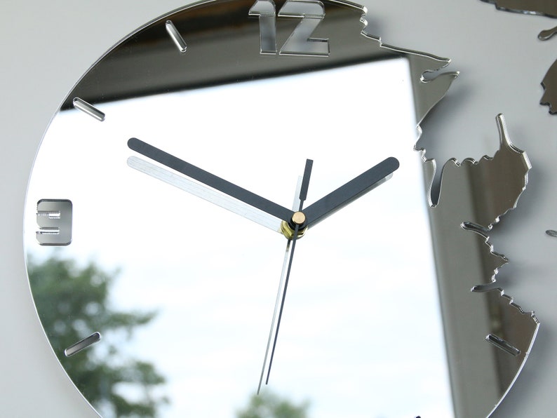 May include: A silver mirrored clock with black hands and a 12 at the top. The clock is designed to look like a broken mirror with a jagged edge.