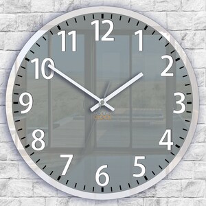 Könnte beinhalten: Eine runde Uhr mit silbernem Rahmen, grauem Zifferblatt und weißen Zahlen. Die Zeiger der Uhr sind weiß und die Uhr ist auf 12:00 Uhr eingestellt.