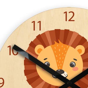 Puede incluir: Un reloj de madera con una cara de le&oacute;n en el centro. La esfera del reloj tiene agujas negras y n&uacute;meros marrones. El le&oacute;n tiene una melena marr&oacute;n, pelaje naranja y ojos negros.