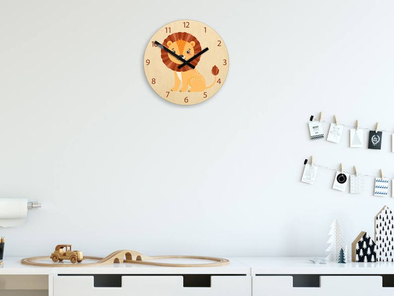Puede incluir: Un reloj de madera con una ilustraci&oacute;n de le&oacute;n y agujas negras. La esfera del reloj tiene los n&uacute;meros del 1 al 12 y el le&oacute;n es naranja y marr&oacute;n.