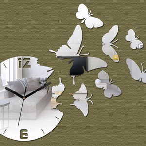 May include: A white mirrored clock with black hands and Roman numerals. The clock is surrounded by a design of white mirrored butterflies.