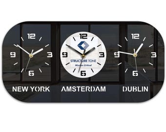 May include: A black and white wall clock showing three time zones: New York, Amsterdam, and Dublin. The central clock face features the text "STRUCTURE TONE Mission Critical". The clock has a rectangular shape with rounded edges.