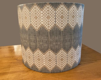 May include: A cylindrical lampshade with a geometric pattern in shades of gray, beige, and white. The pattern features a series of interlocking diamonds and triangles.