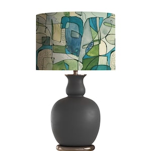 May include: A black ceramic table lamp with a drum shade featuring an abstract design in shades of blue, green, and beige.