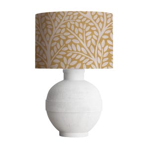 May include: White ceramic table lamp with a round base and a yellow floral patterned lampshade.