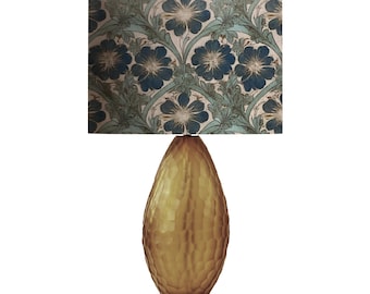 May include: A gold table lamp with a textured glass base and a floral patterned lampshade. The lampshade features blue and green flowers on a white background.