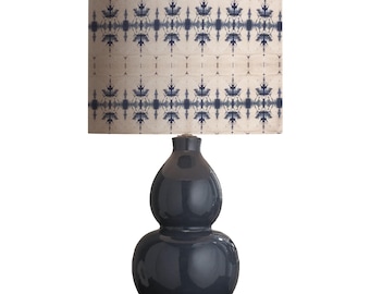 May include: A dark blue ceramic table lamp with a double gourd-shaped base and a white drum lampshade with a blue geometric pattern.