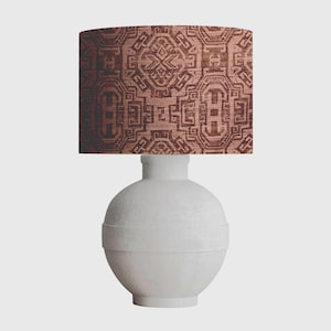 May include: A white ceramic table lamp with a round base and a brown patterned lampshade. The lampshade has a geometric design.