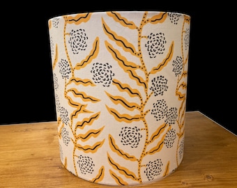 May include: A white lampshade with a yellow and black floral pattern. The pattern features stylized flowers and leaves.
