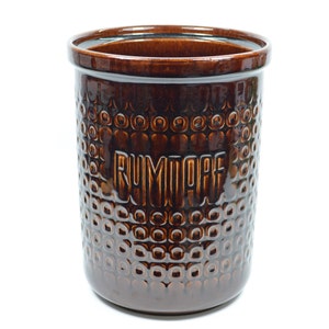 Könnte beinhalten: Eine braune Keramikdose mit strukturierter Oberfläche und dem Wort "RUMMAGE" auf der Vorderseite.
