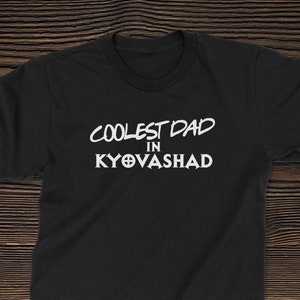 Puede incluir: Camiseta negra con texto blanco que dice "Coolest Dad in Kyovasha".
