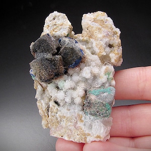 May include: A cluster of blue azurite, green malachite, and black goethite crystals on a white calcite matrix.