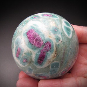 Può includere: Una sfera verde e bianca con vortici rosa e bianchi. La sfera è fatta di pietra lucidata.