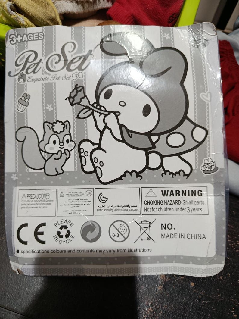 May include: A black and white illustration of a cartoon character holding a flower. The character is wearing a hooded dress with polka dots. The image also includes a squirrel and the text "Pet Set Exquisite Pet Set". The packaging includes a warning label that reads "CHOKING HAZARD - Small parts. Not for children under 3 years."